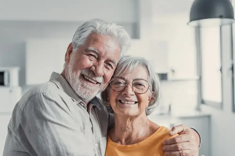 Happy senior couple smiling together in a bright dental office setting.