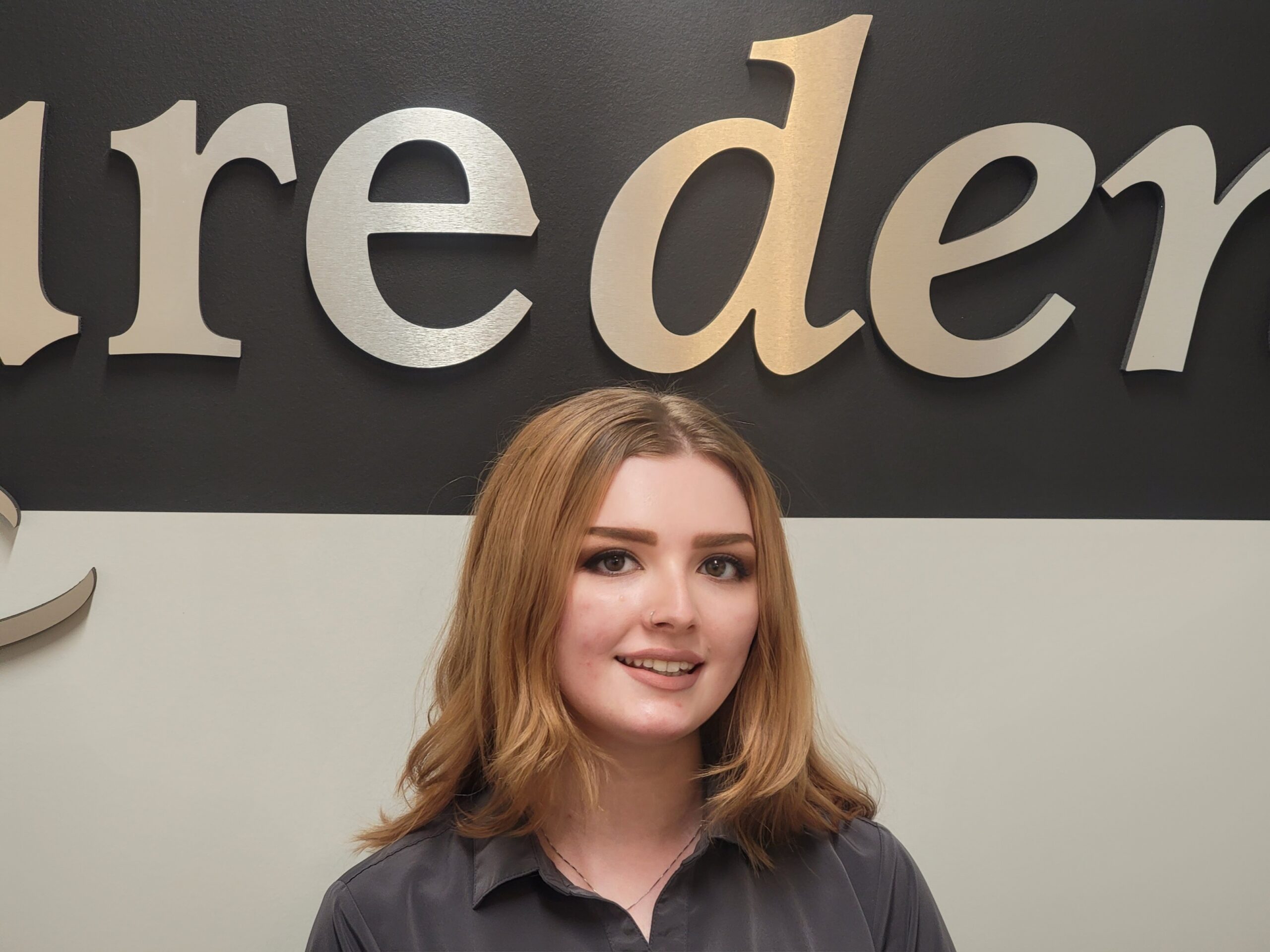 Young woman smiling at Pure Dental event or location with branded backdrop behind her.