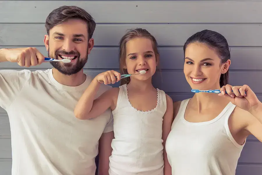 Happy family brushing teeth together, promoting preventive dental care for all ages.