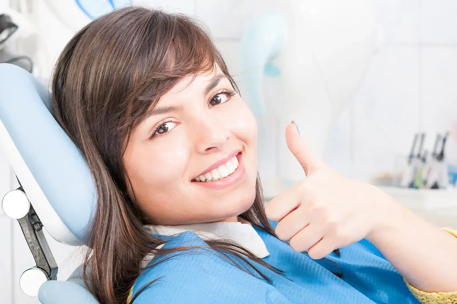 Young woman giving thumbs up in dental chair at Lake Ridge dental practice.