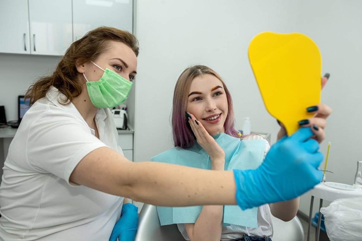 Dentist showing patient yellow shade guide for tooth color matching during smile consultation.