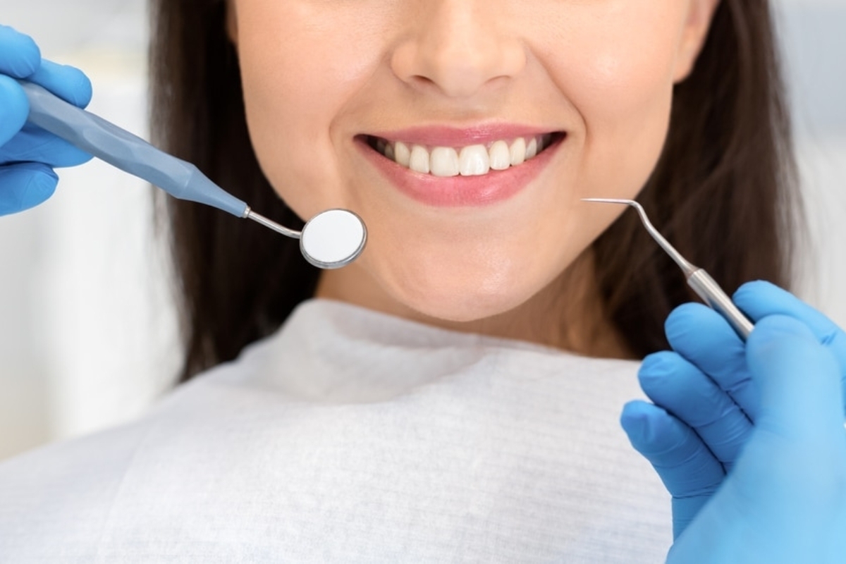Dentist examining patient's teeth with mirror and explorer during cosmetic dental consultation.