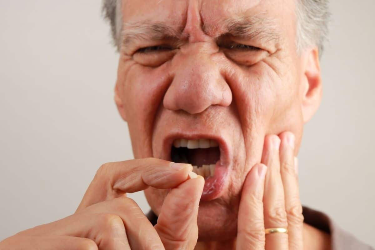 Man experiencing tooth pain, holding his cheek and jaw in discomfort.