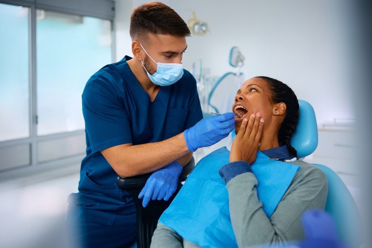 Dentist examining patient's mouth during dental checkup in modern office.