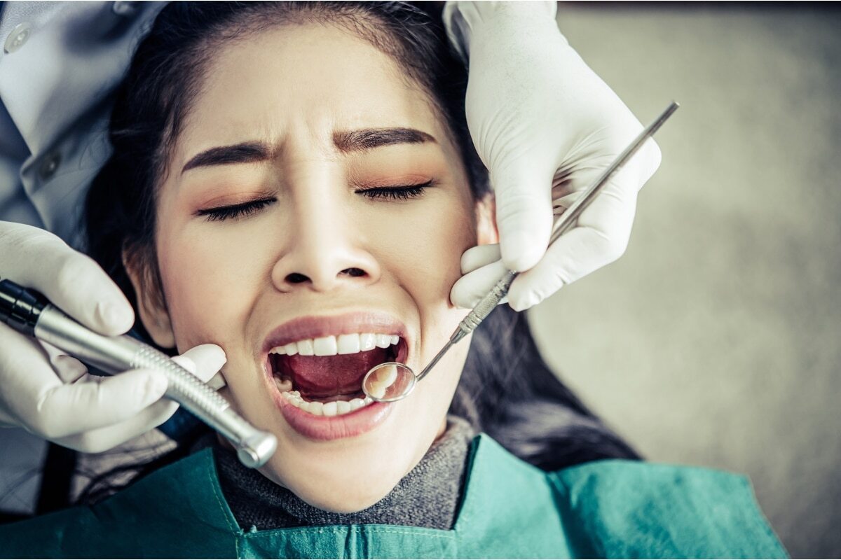 Patient receiving dental examination with professional tools during tooth extraction procedure.