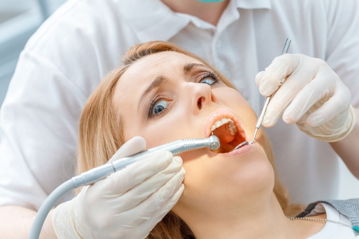 Dentist examining patient's teeth during routine dental checkup and cleaning.