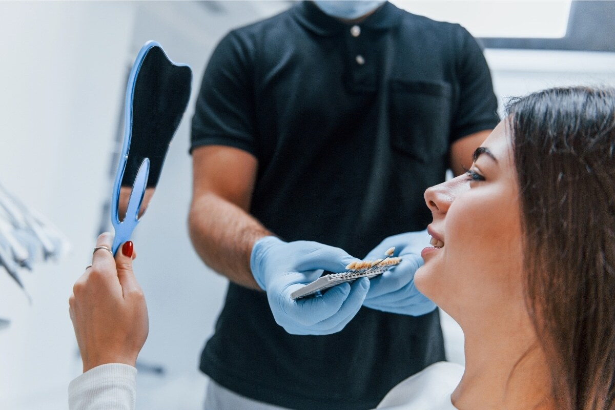 Dentist showing patient smile shade guide during cosmetic dental consultation.