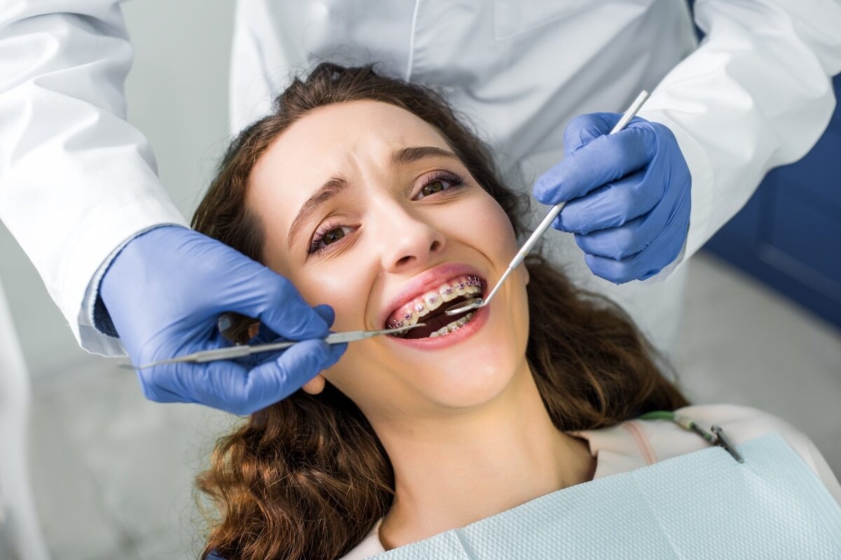 Dentist examining patient with braces during orthodontic treatment consultation.